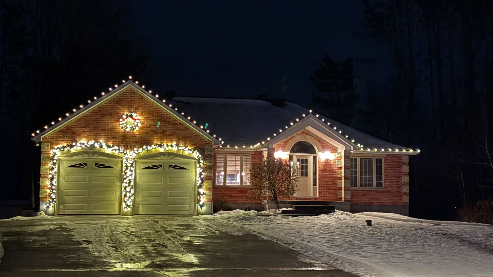 Brick Ottawa home with roofline bulbs, illuminated garage garland, and a Christmas wreath