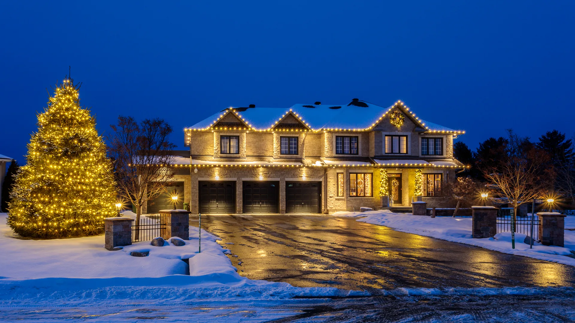 Ottawa residence with a lit Christmas tree, warm-white roofline lights, and snow at blue hour