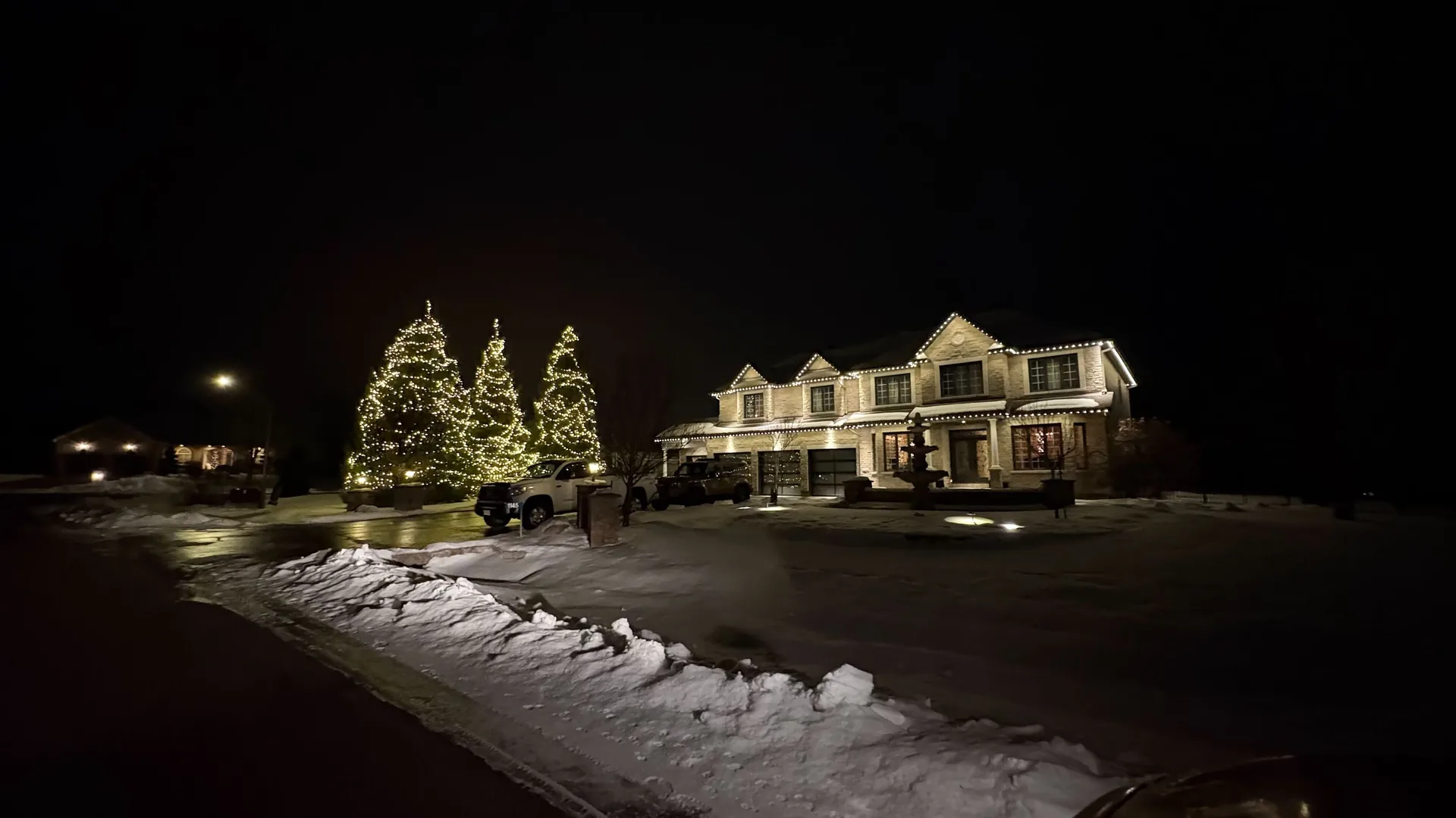 Large Ottawa home with illuminated trees and professional warm-white Christmas roofline lighting